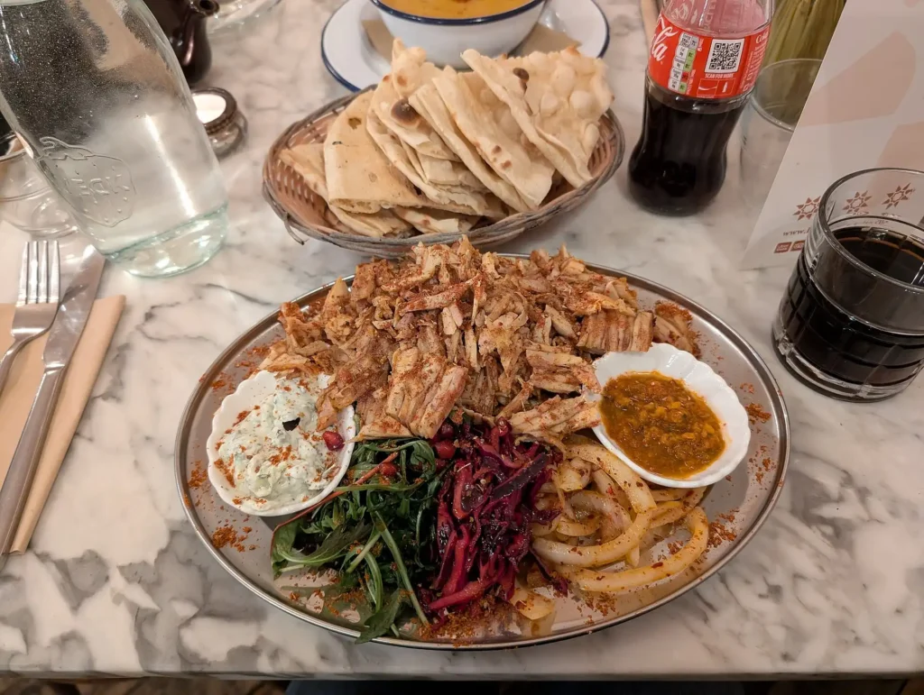 hawarma meat served on a plate with flatbread, sauces, and vegetables